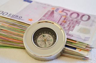 Foto: Geldscheine mit eine Kompass davor